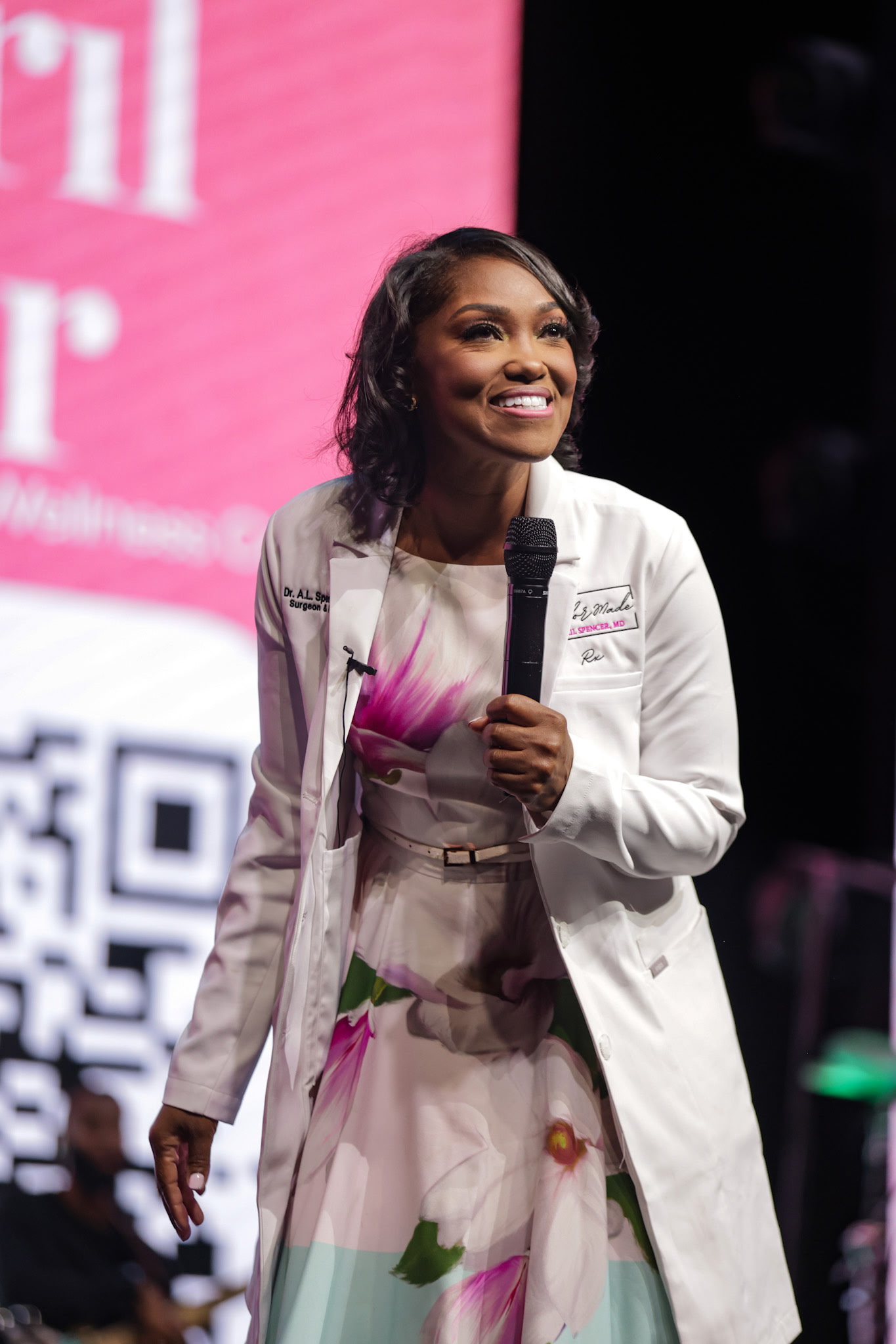 Dr. April Spencer smiling with a microphone during Pop of Pink at Belong Church